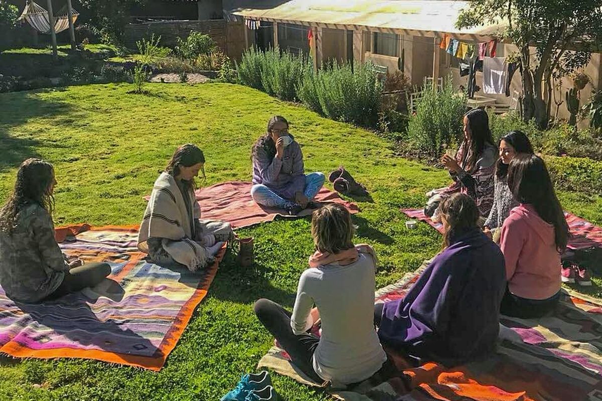 Grupo de personas sentadas sobre mantas en un jardín andino